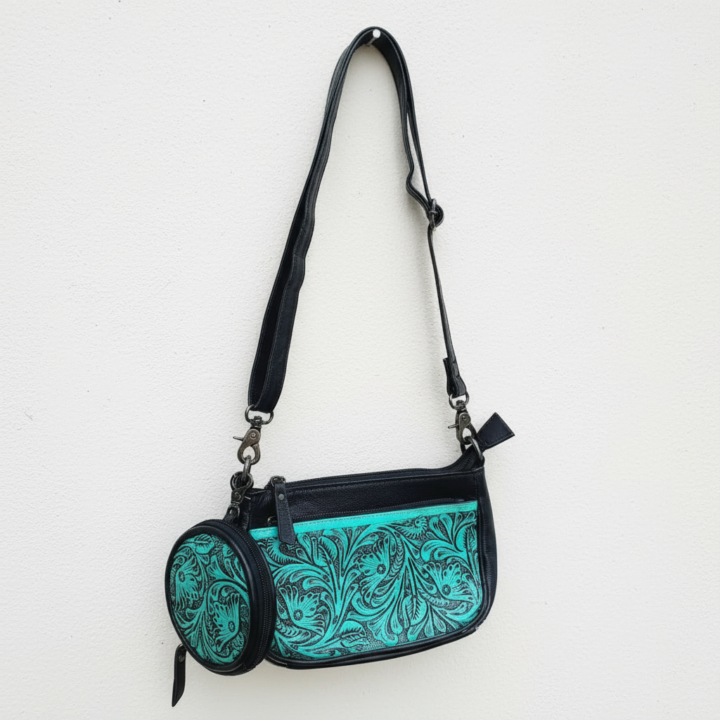 Turquoise handbag with black floral pattern on a white background